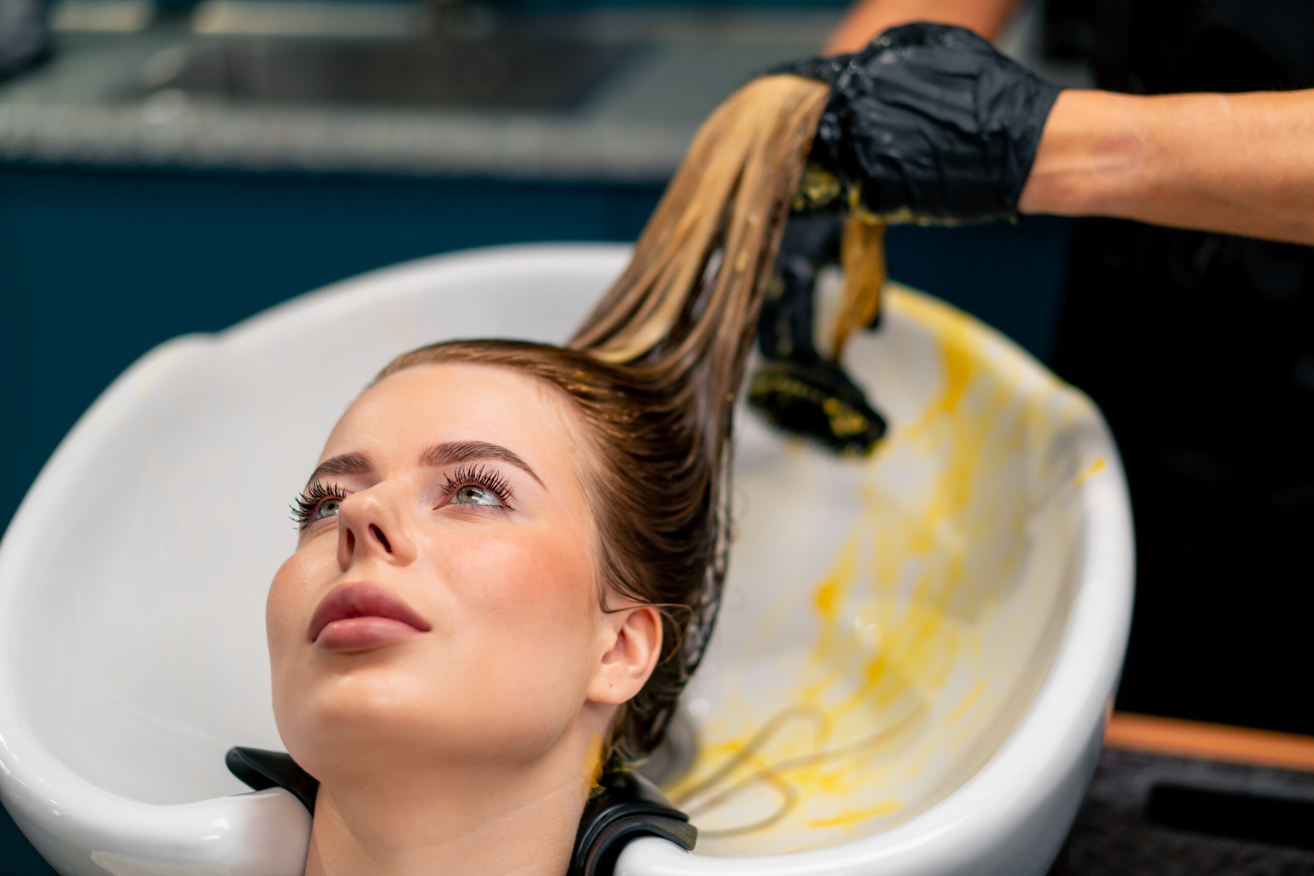 close-up of a hairdresser applying paint to a client's wet hair in beauty salon makeover